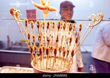 China Beijing Scorpions, cavallucci marini e stelle marine al mercato notturno di Donghuamen, situato all'estremità settentrionale di Wangfujing. Foto Stock