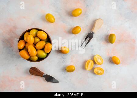 Vista dall'alto dei kumquat nella ciotola e sul terreno Foto Stock