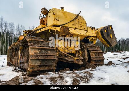 Vecchia attrezzatura bulldozer da costruzione difettosa abbandonata. Trattore cingolato smontato in cantiere. Posatubi rotto. Foto Stock