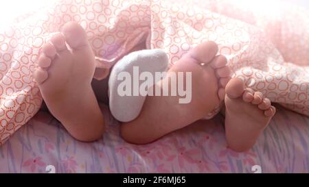 Due sorelle mostrano i loro piedi alla fine del letto alla mattina.Foto con fuoco morbido sui loro piedi. Foto Stock