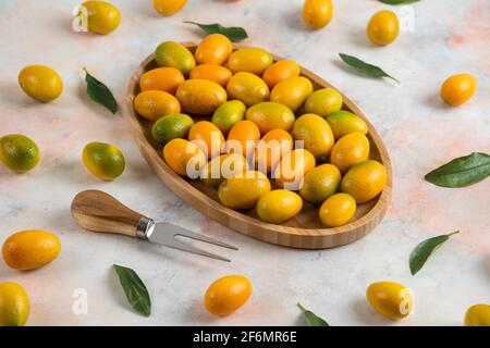 Primo piano foto, pila di kumquat su piastra di legno Foto Stock