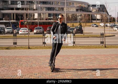 Uomo moderno che guida scooter elettrico in città Foto Stock