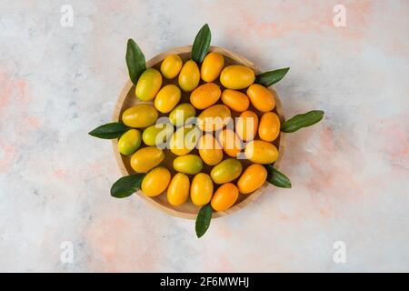Primo piano foto, pila di kumquat su piastra di legno Foto Stock