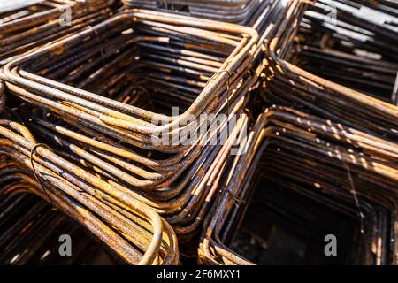 Primo piano sui telai in ferro dell'armatura da costruzione sul altri materiali da costruzione nel cantiere in giornata di sole Foto Stock
