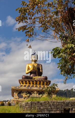 Statua di Buddha al parco del Buddha con cielo blu e. nuvole sullo sfondo e rami sui lati a. Ravangla a Sikkim India il 04 novembre 2016 Foto Stock