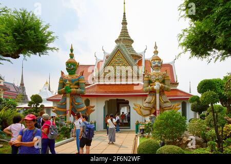 I turisti che prendono selfie di fronte all'ingresso di Wat Arun, il Tempio dell'Alba, sorvegliato da due statue giganti di Yaksha, o la statua di Demon Guardian. Foto Stock