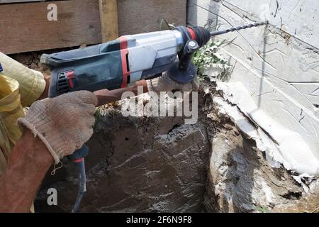 Foratura di un foro nella parete di calcestruzzo con martelletto, perforatore in operazione.nuovo Foto Stock