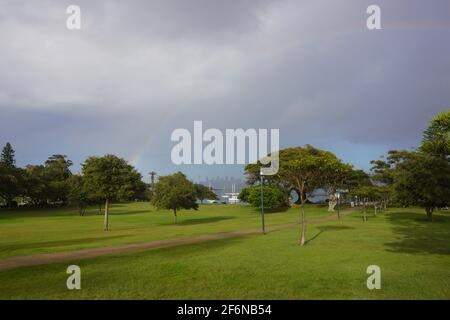 Rainbow su un parco pubblico con lo skyline di Sydney sul Orizzonte Foto Stock