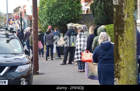 Brighton UK 2 aprile 2021 - centinaia di clienti si accodano intorno al blocco per acquistare mazzi di croce calda da Ravens Bakery a Brighton il Venerdì mattina di Santo . La panetteria è diventata famosa per i suoi panini caldi e le code si formano all'inizio della mattina ogni anno per comprarli: Credit Simon Dack / Alamy Live News Foto Stock