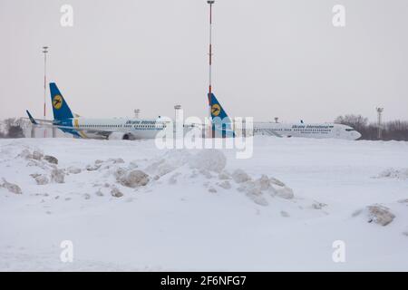 Ucraina, Kiev - 12 febbraio 2021: Aerei in inverno. Velivolo. C'è molta neve all'aeroporto. Cattive condizioni meteorologiche e visibilità. Blocchi di neve. Nevicate. C'è molta neve all'aeroporto. Foto Stock