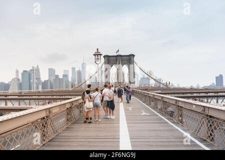 New York City, USA - 6 agosto 2019: Le persone camminano attraverso il famoso Ponte di Brooklyn durante una giornata nuvolosa. Foto Stock