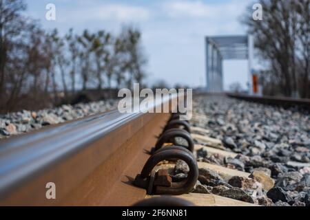 Un primo piano su rotaie e un ponte ferroviario. Foto prospettica scattata in una giornata di sole. Foto Stock