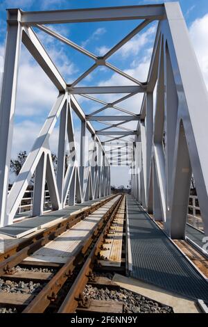 Un primo piano su rotaie e un ponte ferroviario. Foto prospettica scattata in una giornata di sole. Foto Stock