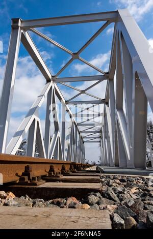 Un primo piano su rotaie e un ponte ferroviario. Foto prospettica scattata in una giornata di sole. Foto Stock