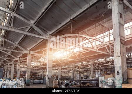 Vecchio abbandonato decadimento industriale fabbrica o impianti di costruzione interni con cemento e acciaio metallo costruzione travi telaio. Luce del sole caldo attraverso Foto Stock