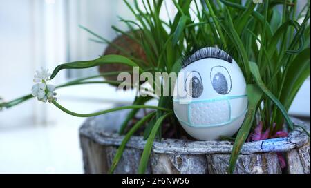 Uovo di pollo pasquale con maschera protettiva in giardino Foto Stock