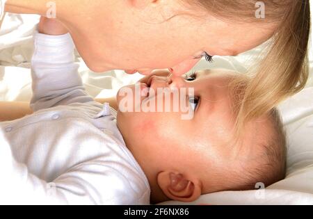 bambino nelle braccia della madre e avvolto in coperta bianca appena è stato curato per dopo avere un buon sonno nella foto di stock di scorta di letto Foto Stock