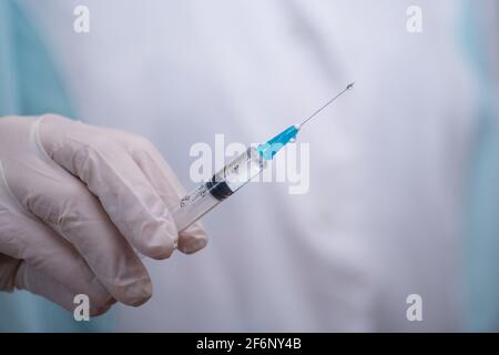 Primo piano della mano guanto del medico che tiene una siringa medica Foto Stock