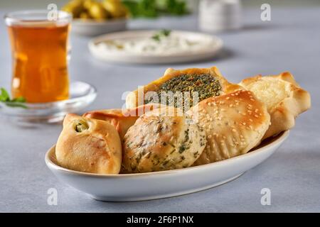 Mediorientale, colazione arabica con pasticceria tradizionale e labneh. Pasties, fatayer o samosa con spinaci, patate e formaggio, manaqeesh zaa Foto Stock