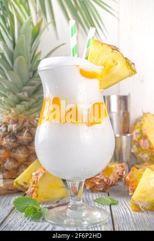 Cocktail moderno tropicale Lava Flow. Bevanda estiva dolce e deliziosa con ananas, rum e crema di cocco. Con ananas a fette e utensili da bar, su Foto Stock