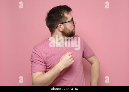 Profilo di un uomo caucasico spaventato e sorpreso con occhiali che guardano ansiosamente al fianco. Sfondo rosa. Foto Stock