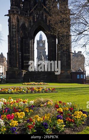 Centro di Edimburgo, Scozia, tempo del Regno Unito. 2 aprile 2021. Sole in tranquillo centro città per Pasqua Venerdì Bank Holiday, temperatura 9 gradi centigradi. Nella foto: Giardini di Princes Street East colorati aiuole primaverili con Scott Monument e Torre dell'Orologio Baloral in background. Foto Stock