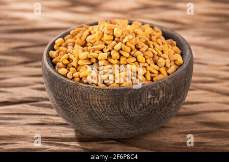 Semi di fenugreek organici in ciotola di legno - Trigonella foenum - graecum Foto Stock