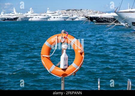 Concetto Lifebuoy. Boa arancione, cintura di salvataggio messo su ferro verticale argento. Supporto, protezione, sicurezza a Marina Flisvou, Grecia. Aege Foto Stock