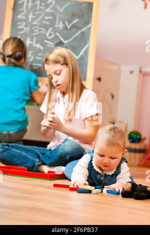 Bambini - sorelle - giocare in casa; un bambino è ancora un bambino Foto Stock