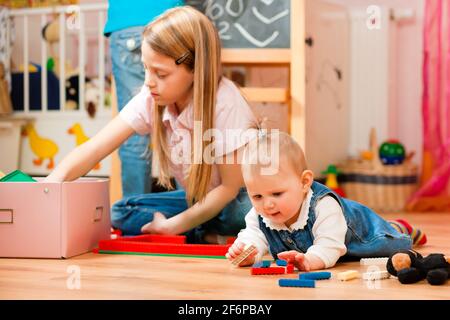 Bambini - sorelle - giocare in casa; un bambino è ancora un bambino Foto Stock