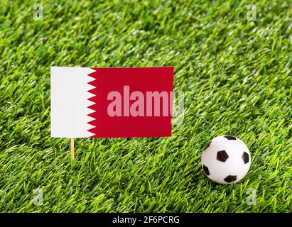 Bandiera nazionale del Qatar con palla di calcio nello stadio Foto Stock