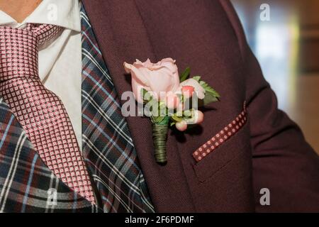 Decorazione floreale sul lapello di un vestito da uomo. Fiore. Boutonniere. Foto Stock