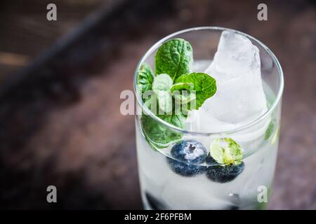 Cocktail mojito mirtillo su sfondo ligneo. Messa a fuoco selettiva. Profondità di campo poco profonda. Foto Stock