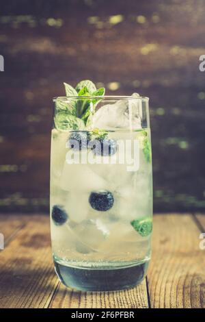 Cocktail mojito mirtillo su sfondo ligneo. Messa a fuoco selettiva. Profondità di campo poco profonda. Foto Stock