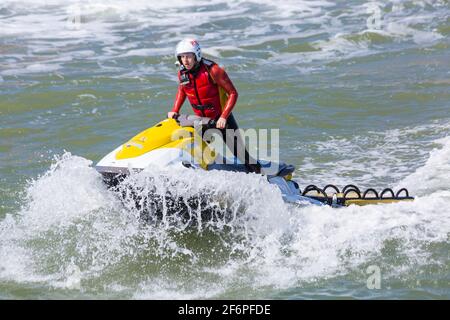 Bournemouth, Dorset UK. 2 aprile 2021. Venerdì di Pasqua. Tempo in Gran Bretagna: Sole e breezy per l'inizio del lungo week-end di Pasqua in riva al mare a Bournemouth spiagge come la gente si dirige verso il mare. RNLI Lifeguard su jetski in pattuglia. Credit: Carolyn Jenkins/Alamy Live News Foto Stock