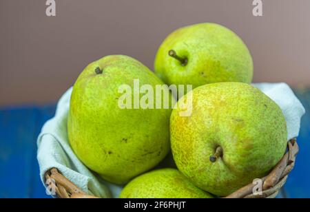 Frutti di pera verde in cesto di legno su sfondo neutro. Frutta ricca di vitamina A, calcio e vitamina C. alimenti a basso contenuto calorico. Infredient per succhi e. Foto Stock