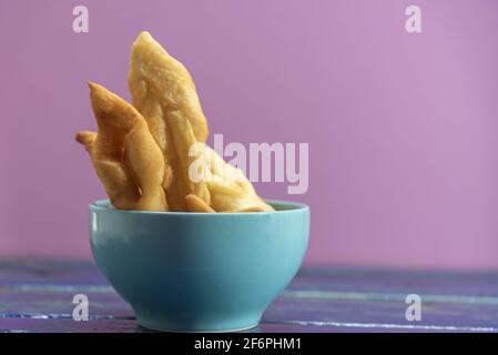 Frappe italiane o chiacchere fatte con pasta di grano in una pentola di porcellana. Prelibatezze e delizie culinarie. Cucina italiana. Impasto di grano fritto con zucchero Foto Stock