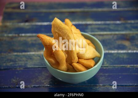 Frappe italiane o chiacchere fatte con pasta di grano in una pentola di porcellana. Prelibatezze e delizie culinarie. Cucina italiana. Impasto di grano fritto con zucchero Foto Stock