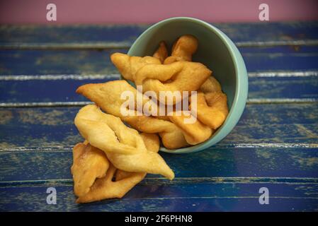 Frappe italiane o chiacchere fatte con pasta di grano in una pentola di porcellana. Prelibatezze e delizie culinarie. Cucina italiana. Impasto di grano fritto con zucchero Foto Stock