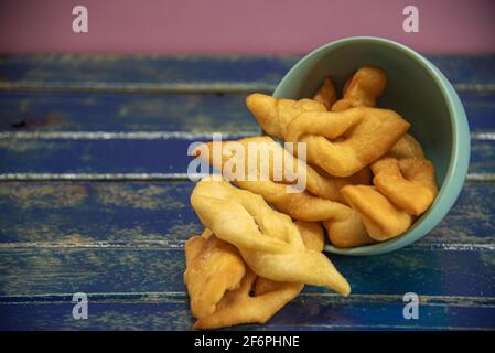 Frappe italiane o chiacchere fatte con pasta di grano in una pentola di porcellana. Prelibatezze e delizie culinarie. Cucina italiana. Impasto di grano fritto con zucchero Foto Stock