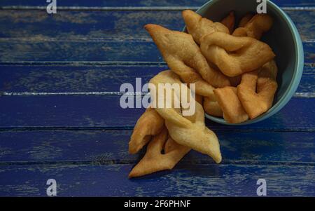 Frappe italiane o chiacchere fatte con pasta di grano in una pentola di porcellana. Prelibatezze e delizie culinarie. Cucina italiana. Impasto di grano fritto con zucchero Foto Stock