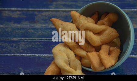 Frappe italiane o chiacchere fatte con pasta di grano in una pentola di porcellana. Prelibatezze e delizie culinarie. Cucina italiana. Impasto di grano fritto con zucchero Foto Stock