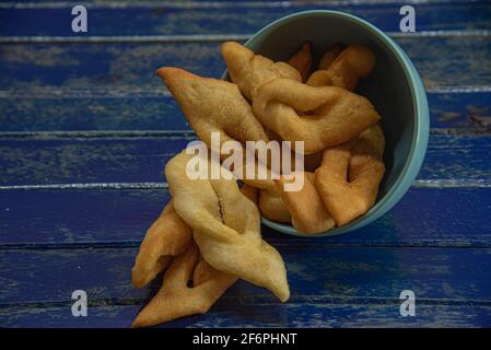 Frappe italiane o chiacchere fatte con pasta di grano in una pentola di porcellana. Prelibatezze e delizie culinarie. Cucina italiana. Impasto di grano fritto con zucchero Foto Stock