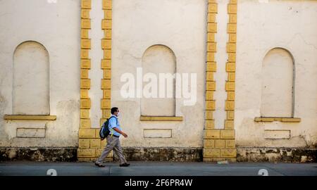 Mumbai, India - 7 gennaio 2021 : uomo indiano non identificato che cammina indossando il marchio di covid e lo zaino con mentre la parete nello sfondo Foto Stock
