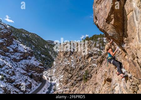 Donna rock climber la naviga su una parete rocciosa in Golden, CO Foto Stock