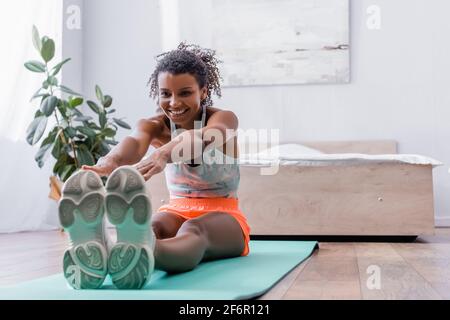 Allegra donna afroamericana che si allunga sul pavimento in camera da letto Foto Stock