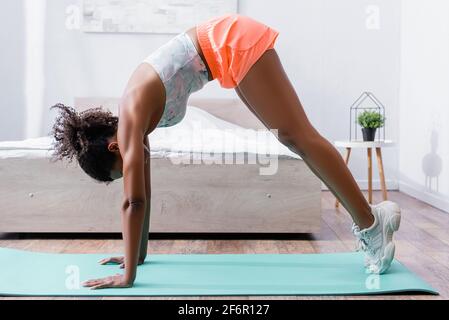 Donna afroamericana in abbigliamento sportivo e sneakers formazione sul fitness mat Foto Stock