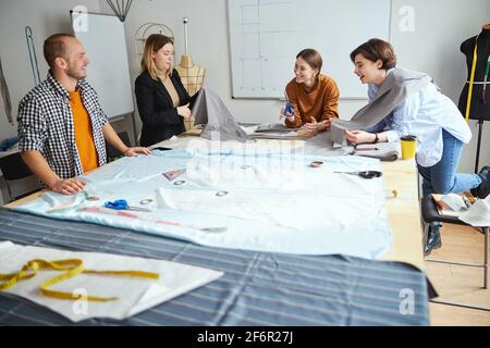 Abbigliamento esperto sartoriale e studente raccogliendo tessuto tagliato Foto Stock