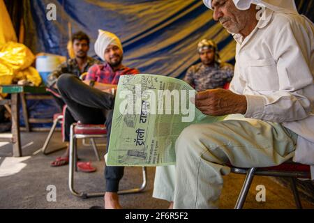 Ghaziabad, India. 02 aprile 2021. Un protestante che ha letto il Trolley Times durante la manifestazione.Farmers ha stabilito il loro proprio giornale chiamato 'Trolley Times' un giornale settimanale di quattro pagine stampato in lingue Gurmukhi e Hindi, fondato nel dicembre 2020 per dare voce alla protesta degli agricoltori. Gli agricoltori indiani protestano sul confine con l'Haryana a Delhi da quattro mesi contro il nuovo progetto di legge. Credit: SOPA Images Limited/Alamy Live News Foto Stock