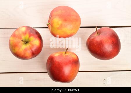 Quattro mele Jonathan rosse, fresche, succose e mature, da vicino, su un banco in legno bianco. Foto Stock